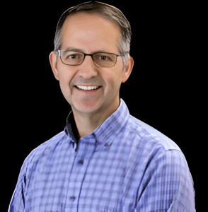 Smiling man in glasses and plaid shirt.